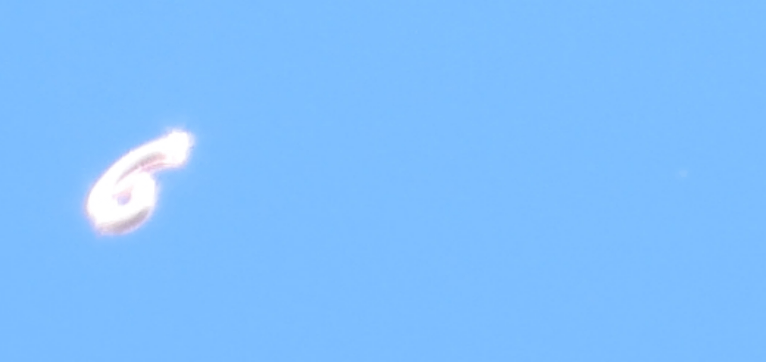 Bent loop-like outline and faint distant patch. A still does not establish co-motion.